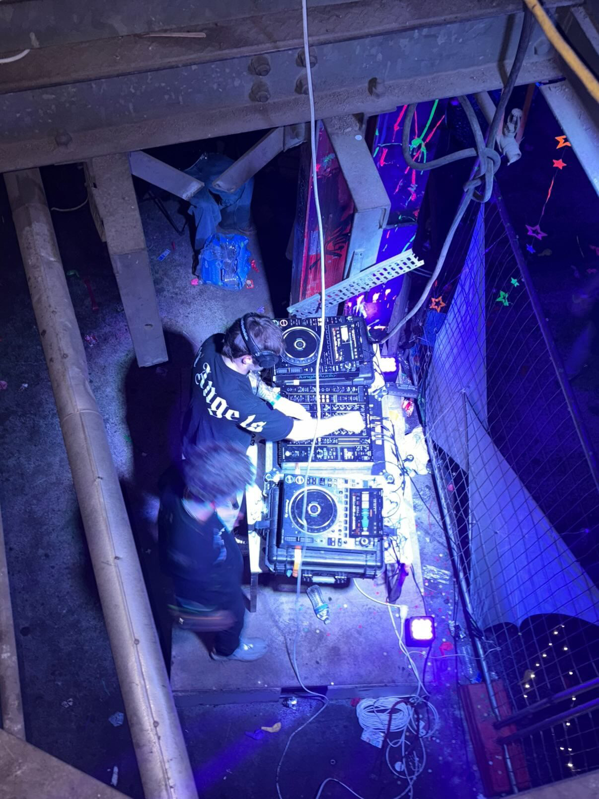 SKITEKK overhead on the CDJs in a UV-lit warehouse